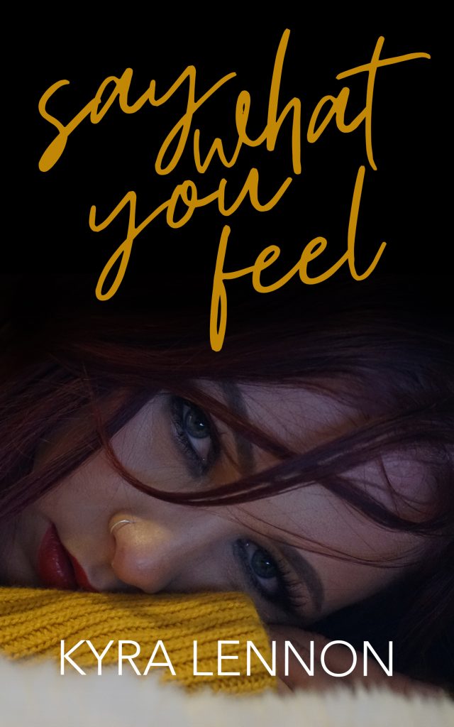 Cover for Say What You Feel featuring a young woman with dark red hair and green eyes, resting her head on her arm. 